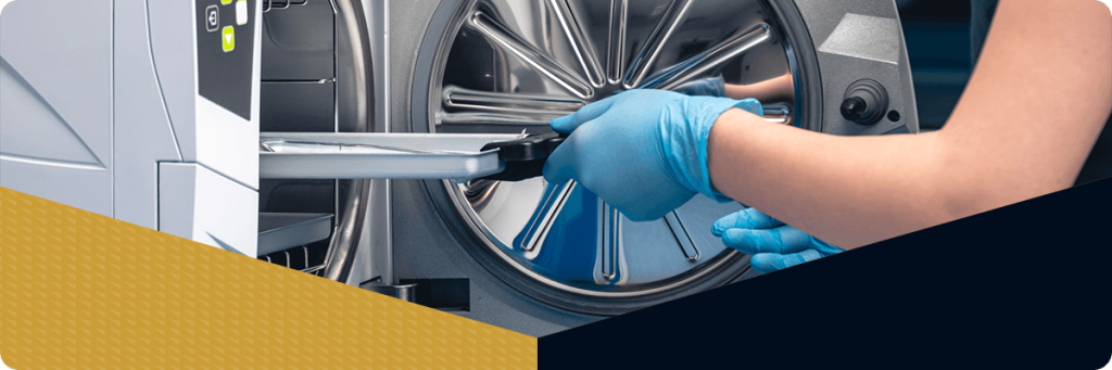 A woman pulls a tray out of the autoclave