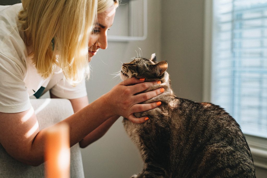 A blonde woman holds her cat's face